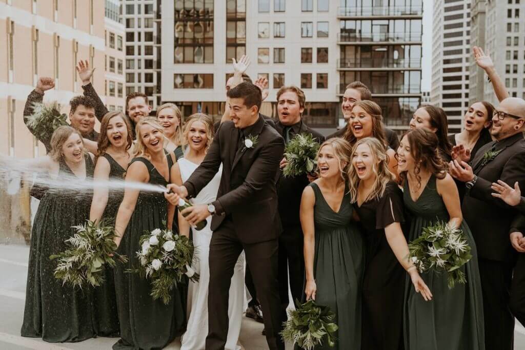 groom shooting off and spraying champagne alongside the wedding party.
