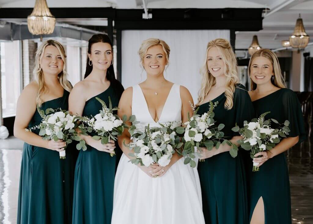 bridesmaids wearing dark green dresses with white dressed bride